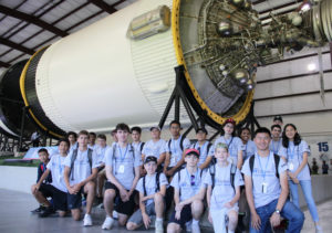 TryEngineering Summer Institute summer engineering camp students on a field trip to NASA and the Johnson Space Center pose in front of a rocket.