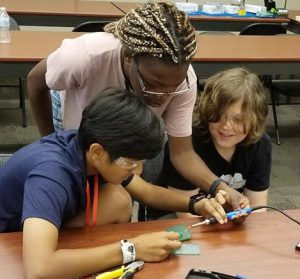 Try Engineering Summer Institute helps two teen students with a soldering project during this exciting STEM camp for teens