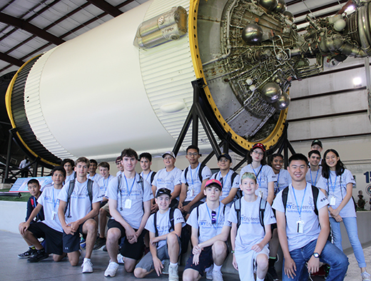 TryEngineering Summer Institute summer STEM camp students pose in front of a rocket during a field trip to NASA and the Johnson Space Center